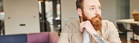 portrait of thoughtful, bearded and tattooed entrepreneur looking away in modern office environment, professional headshot,  business lifestyle concept, banner with copy space