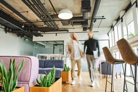 motion blur of entrepreneur with laptop walking next to business partner and discussing startup in office lounge with high tech interior, modern furniture, natural plants, dynamic business concept