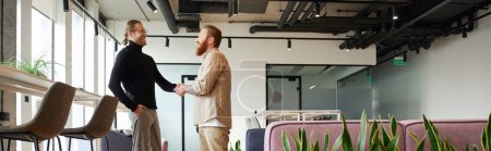 Photo for Side view of entrepreneur in stylish casual clothes shaking hands with bearded and tattooed business partner and closing deal in contemporary coworking office with high tech interior, banner - Royalty Free Image