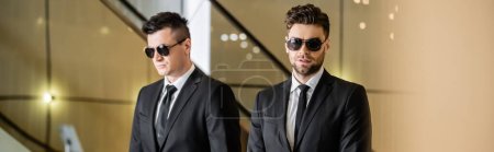 security management of luxury hotel, two handsome men in formal wear and sunglasses, bodyguards on duty, safety measures, vigilance, suits and ties, private security, strong guards, banner 