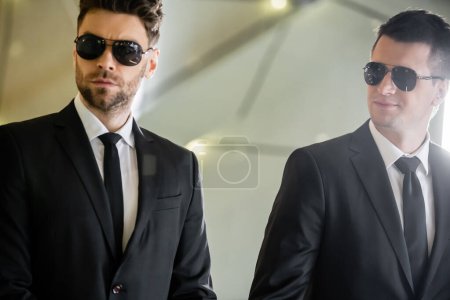 security management, two handsome men in formal wear and sunglasses, bodyguards on duty, safety measures, vigilance, suits and ties, private security, strong guards in luxury hotel