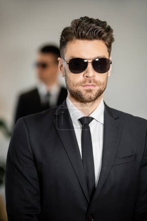 bodyguard service, handsome man in sunglasses and black suit with tie, hotel safety, security management, surveillance and vigilance, uniformed guard on duty, professional headshots