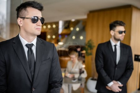 private security service, personal safety concept, handsome bodyguards in formal wear and sunglasses protecting safety of female client on blurred background, mother and daughter in cafe 