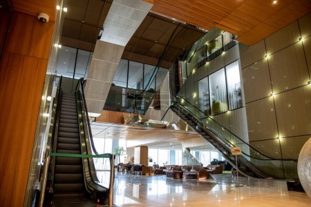 Téléchargez les photos : Intérieur moderne de l'hôtel avec design sophistiqué lobby, escaliers mécaniques, escalier mobile, canapés en cuir chic, ambiance somptueuse, spacieux et confort, élégance et chic, esthétique - en image libre de droit