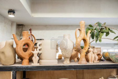 Clay figures and sculptures on rack in blurred ceramic workshop