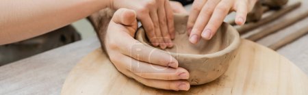 Téléchargez les photos : Vue recadrée du couple d'artisan façonnant bol d'argile ensemble dans un studio de céramique, bannière - en image libre de droit