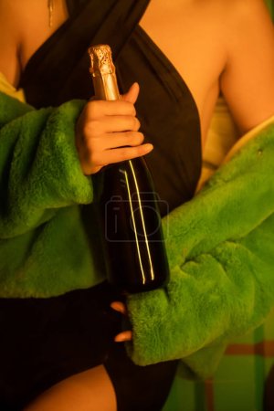 Ausgeschnittene Ansicht einer stilvollen Frau in Kleid und Jacke mit Champagner in der Nähe von Rauch in einem Nachtclub