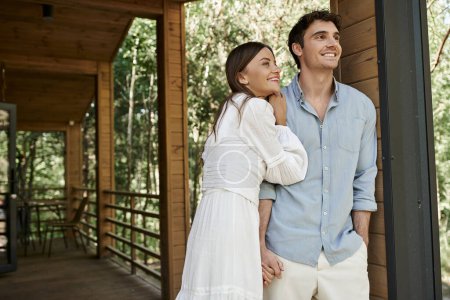 happy man standing with hand in pocket near beautiful woman in sundress, summer house, vacation