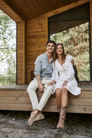 casa de vacaciones, romance de verano, hombre abrazando a la hermosa mujer y sentado en el porche, pareja feliz
