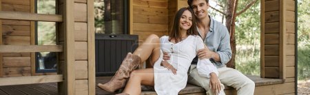 romantic getaway, man hugging happy woman with tattoo while sitting on porch of vacation house