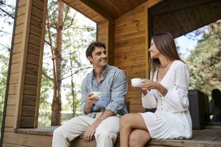 escapada romántica, hombre y mujer sosteniendo tazas de café de la mañana, pareja en el porche de la casa de vacaciones