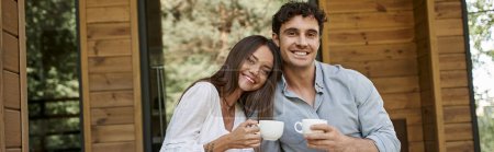 banner, cheerful couple holding cups of coffee, man and woman laughing on porch of vacation house