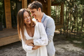 laughter, happy man hugging cheerful woman in sundress near vacation house, summer love, romance puzzle #666378288