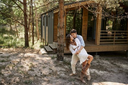 Mann umarmt Frau in der Nähe von Ferienhaus, im Wald, Sommer und Romantik, Glück und Lachen