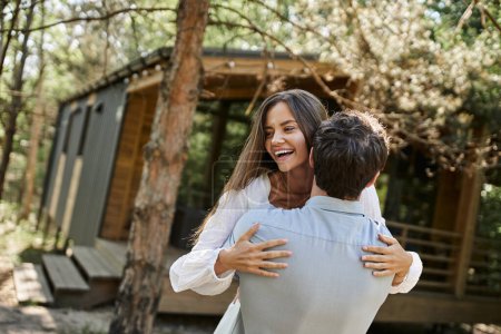 handsome man hugging happy woman in white sundress, vacation house near forest, romance and love