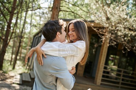 happy man and woman hugging and looking at each other, vacation house in forest, romance and love