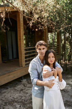 handsome man hugging beautiful woman, couple standing near vacation house, people and nature