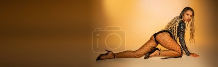 banner, seductive african american woman crawling on yellow background, fishnet tights, high heels