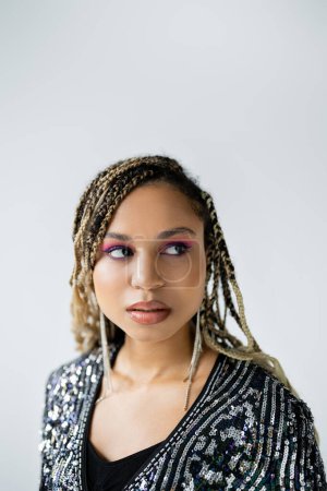 portrait of dreamy african american woman looking away on grey background, bold makeup, attractive