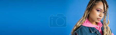 Téléchargez les photos : Bannière, belle femme afro-américaine avec dreadlocks regardant la caméra sur fond bleu - en image libre de droit