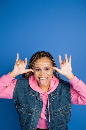 positive afrikanisch-amerikanische Frau ausgestreckte Zunge auf blauem Hintergrund, Spaß und Glück, Freude