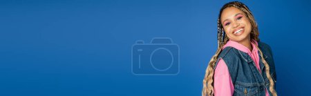 Banner, fettes Make-up, fröhliche afrikanisch-amerikanische Frau lächelt und blickt in die Kamera auf blauem Hintergrund