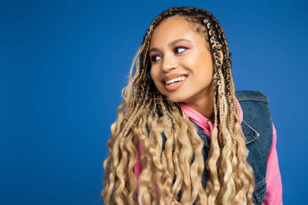 beautiful african american woman with dreadlocks and long hair looking away on blue background