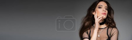 Moda joven modelo asiático con maquillaje usando top de malla y collares aislados en gris, bandera