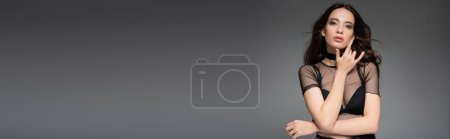 Attrayant asiatique femme en mesh top et colliers regardant caméra isolée sur gris, bannière