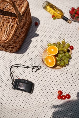 Photo for Summer picnic concept, food, bottle, wine, wicker basket, oranges, grapes, vintage camera, top view - Royalty Free Image