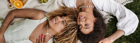 Téléchargez les photos : Vue du dessus des femmes afro-américaines riantes reposant sur une couverture pendant le pique-nique d'été - en image libre de droit