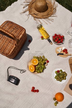picnic concept, grapes, strawberries, cherry tomatoes, orange, wine, basket, straw hat, top view
