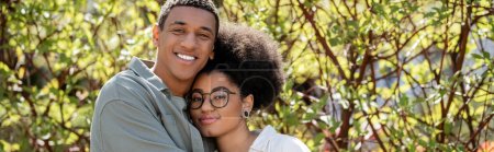joyeux couple afro-américain regardant la caméra ensemble à l'extérieur, bannière