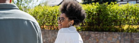 Téléchargez les photos : Femme afro-américaine gaie dans des lunettes de vue regardant petit ami à l'extérieur en été, bannière - en image libre de droit