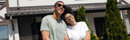 sourire couple afro-américain debout près de la nouvelle maison sur fond extérieur, bannière