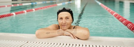 cheerful middle aged woman relaxing at poolside, swim cap and goggles, recreation center, banner