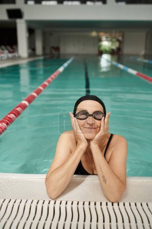 mujer de mediana edad en gorra de natación y gafas, piscina, centro de recreación, tatuaje, junto a la piscina