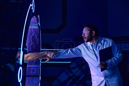 amazed indian scientist holding hand appearing from experimental device in innovation hub