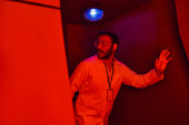 unknown phenomenon, scared indian scientist looking away in red neon light in innovation hub magic mug #668555442