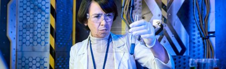 Photo for Middle aged woman scientist in goggles looking at liquid in test tube in innovation lab, banner - Royalty Free Image