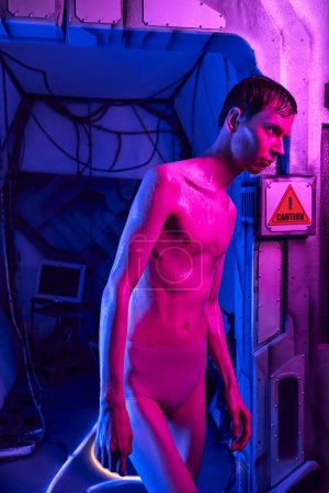 humanoïde inconnu étranger, voyageur cosmique debout dans la lumière néon du laboratoire innovant futuriste