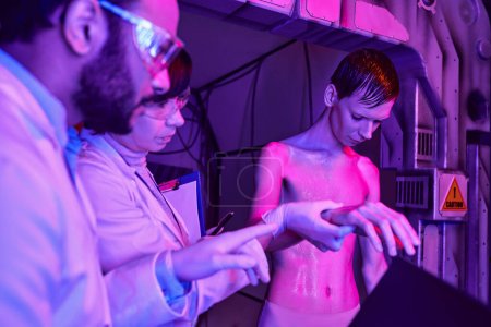 scientifiques multiethniques examinant humanoïde extraterrestre dans un centre scientifique, exploration de la vie extraterrestre