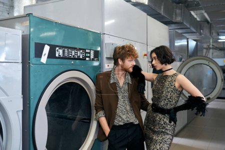 fashionable young asian woman standing near redhead boyfriend in public laundry