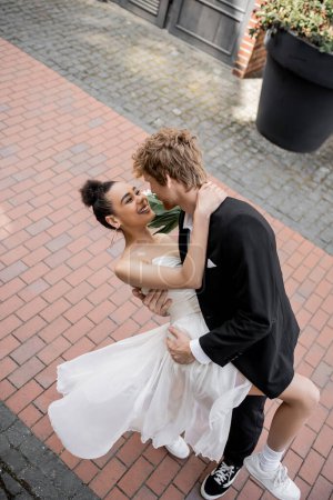 Photo for Love in city, elegant multiethnic couple hugging on street, joy, happiness - Royalty Free Image