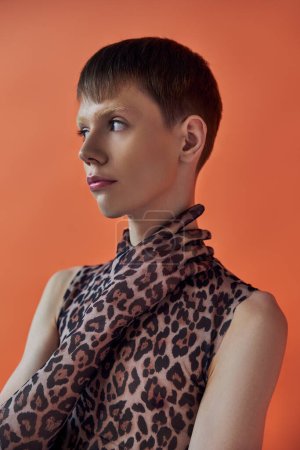 queer person, fashion concept, young man posing on orange backdrop, animal print, leopard print