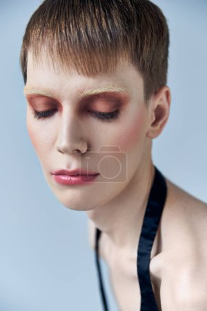 portrait, androgynous model with makeup, grey backdrop, beauty and visage, queer, close up