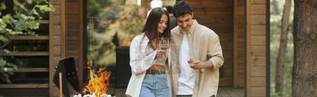 Photo for Positive couple holding wine near grill and blurred vacation house at background, banner - Royalty Free Image