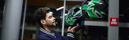 handsome man choosing helmet for karting inside of karting locker room, motorsport concept, banner