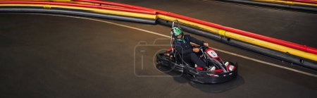 Photo for African american man in go-kart on circuit, racing inside of indoor karting track, banner - Royalty Free Image