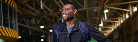 Téléchargez les photos : Joyeux homme afro-américain en vêtements de sport debout près de go-kart en piste de karting, bannière horizontale - en image libre de droit
